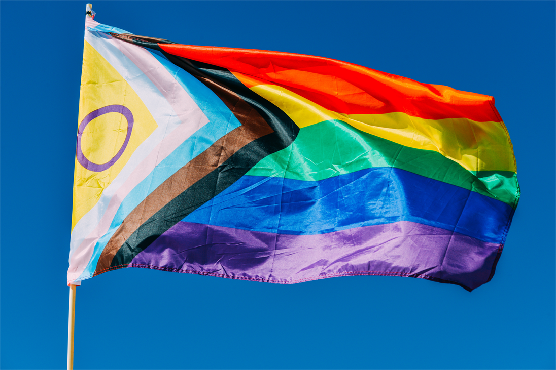 Wehende Regenbogenflagge vor blauem Himmel